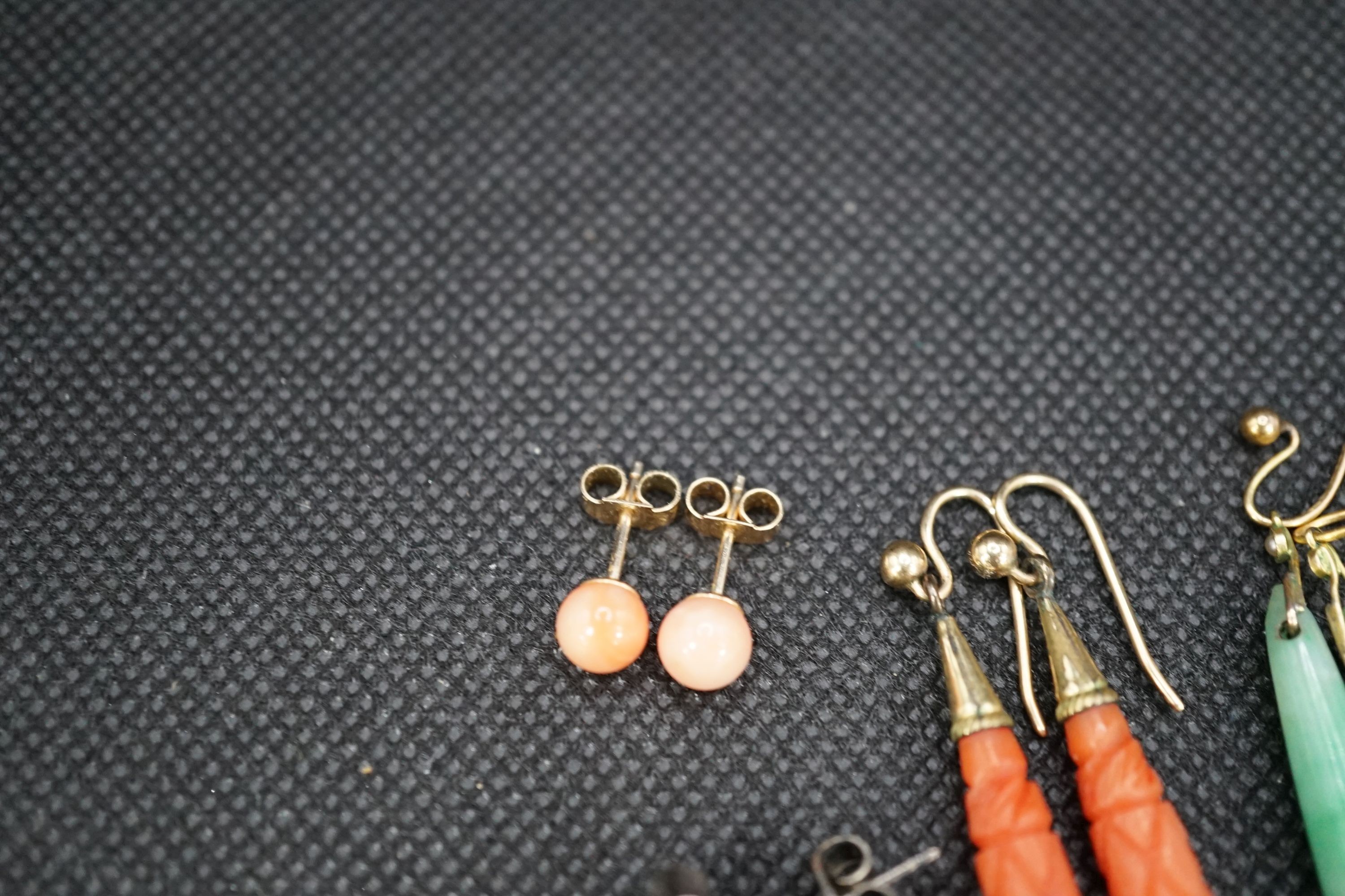 A pair of gilt metal and carved coral set teardrop shaped earrings, 38mm, a pair of similar shaped jade earrings and two other pairs of ear studs.